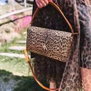 Pochette noire avec anse et bandoulière décorée de détails dorés