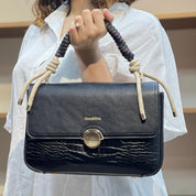 Sac à main avec anse en corde nouée et fermeture métallique.