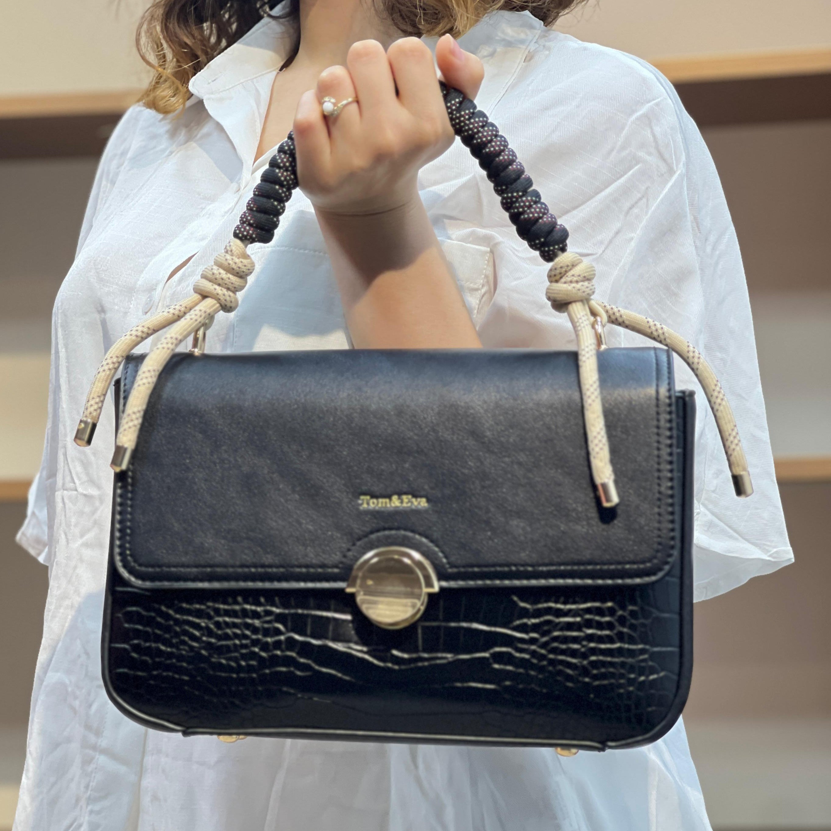 Sac à main avec anse en corde nouée et fermeture métallique.