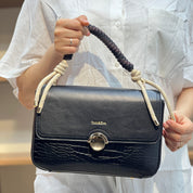 Sac à main avec anse en corde nouée et fermeture métallique.