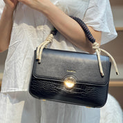 Sac à main avec anse en corde nouée et fermeture métallique.