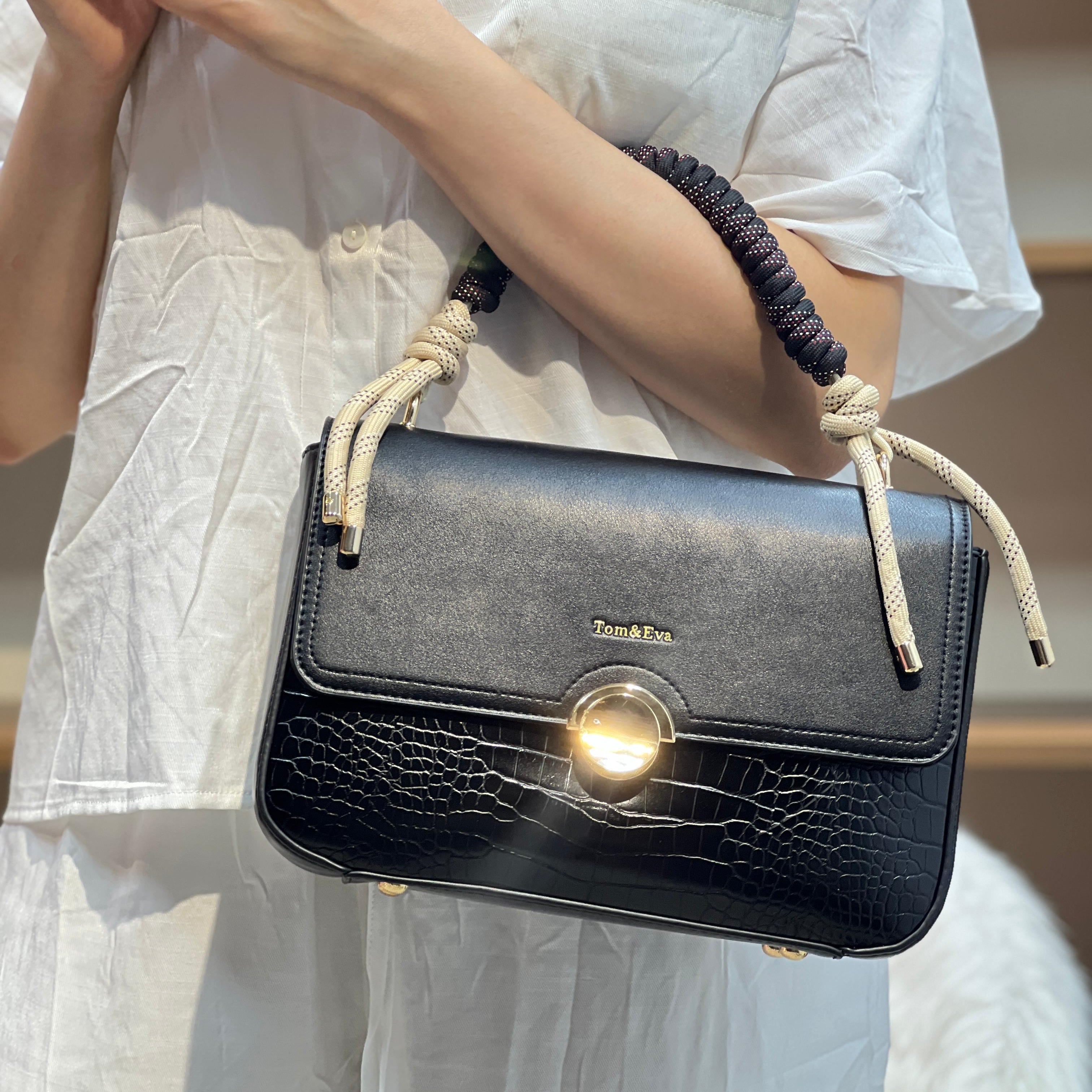 Sac à main avec anse en corde nouée et fermeture métallique.