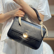 Sac à main avec anse en corde nouée et fermeture métallique.