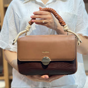 Sac à main avec anse en corde nouée et fermeture métallique.