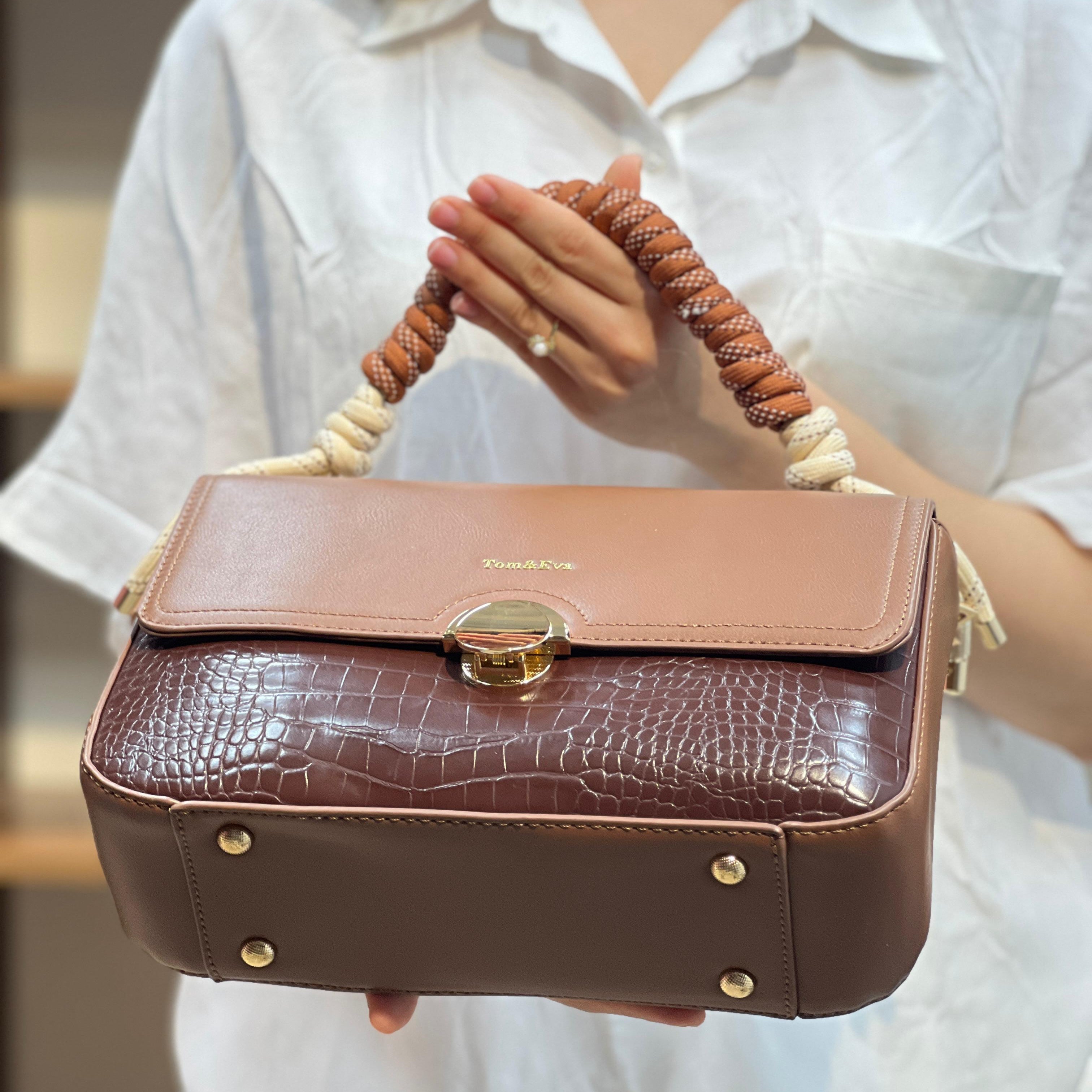 Sac à main avec anse en corde nouée et fermeture métallique.