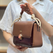 Sac à main avec anse en corde nouée et fermeture métallique.