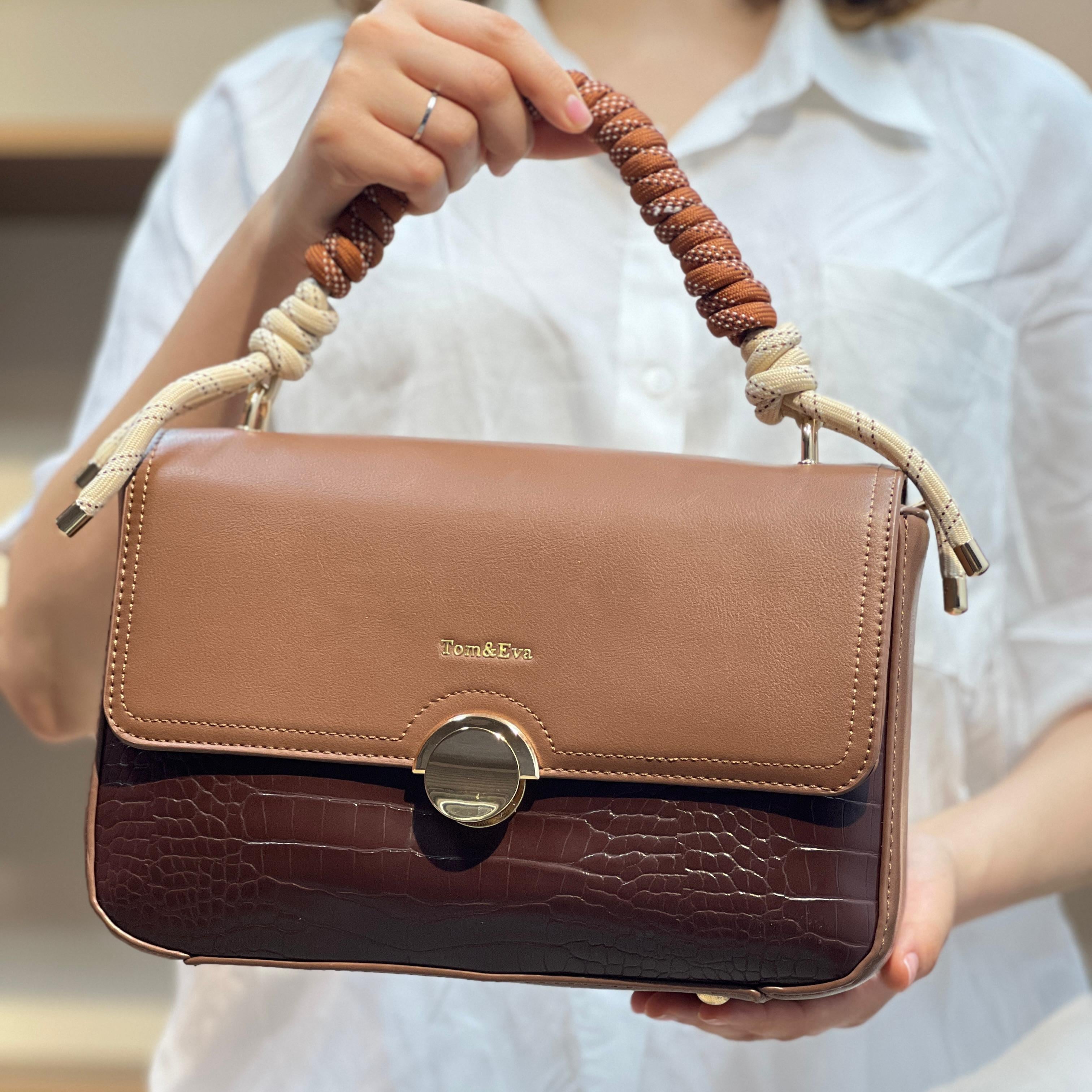 Sac à main avec anse en corde nouée et fermeture métallique.