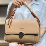 Sac à main avec anse en corde nouée et fermeture métallique.