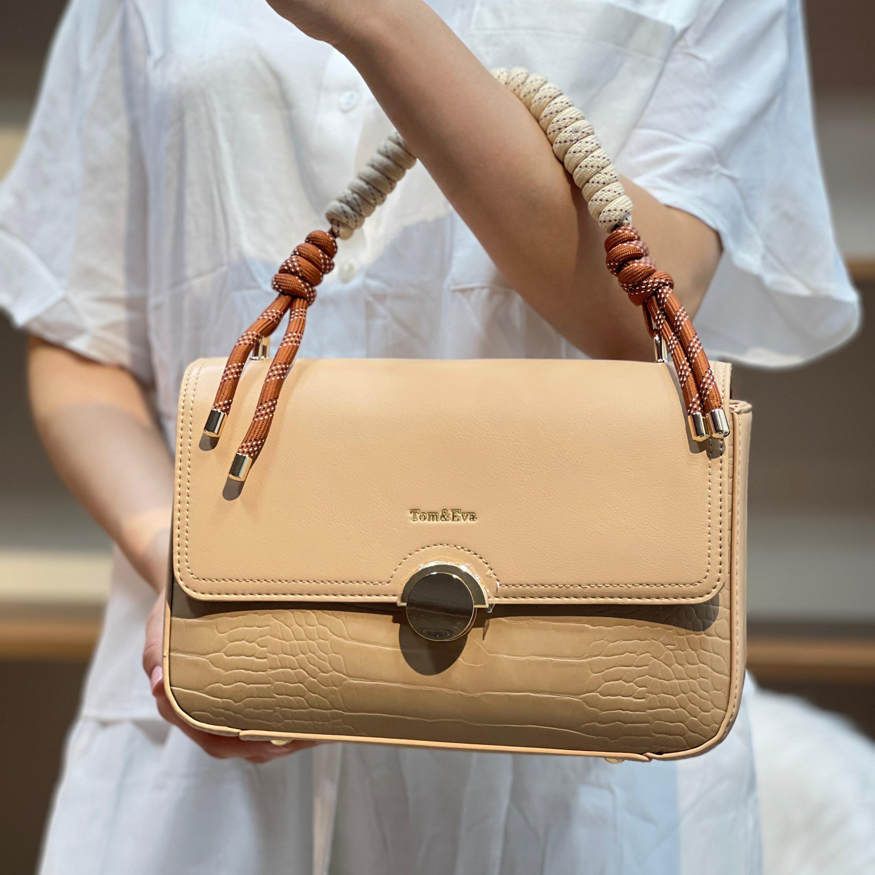 Sac à main avec anse en corde nouée et fermeture métallique.