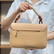 Sac à main avec anse en corde nouée et fermeture métallique.