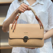 Sac à main avec anse en corde nouée et fermeture métallique.