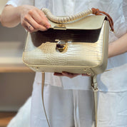 Sac à main avec anse en corde nouée et fermeture métallique.