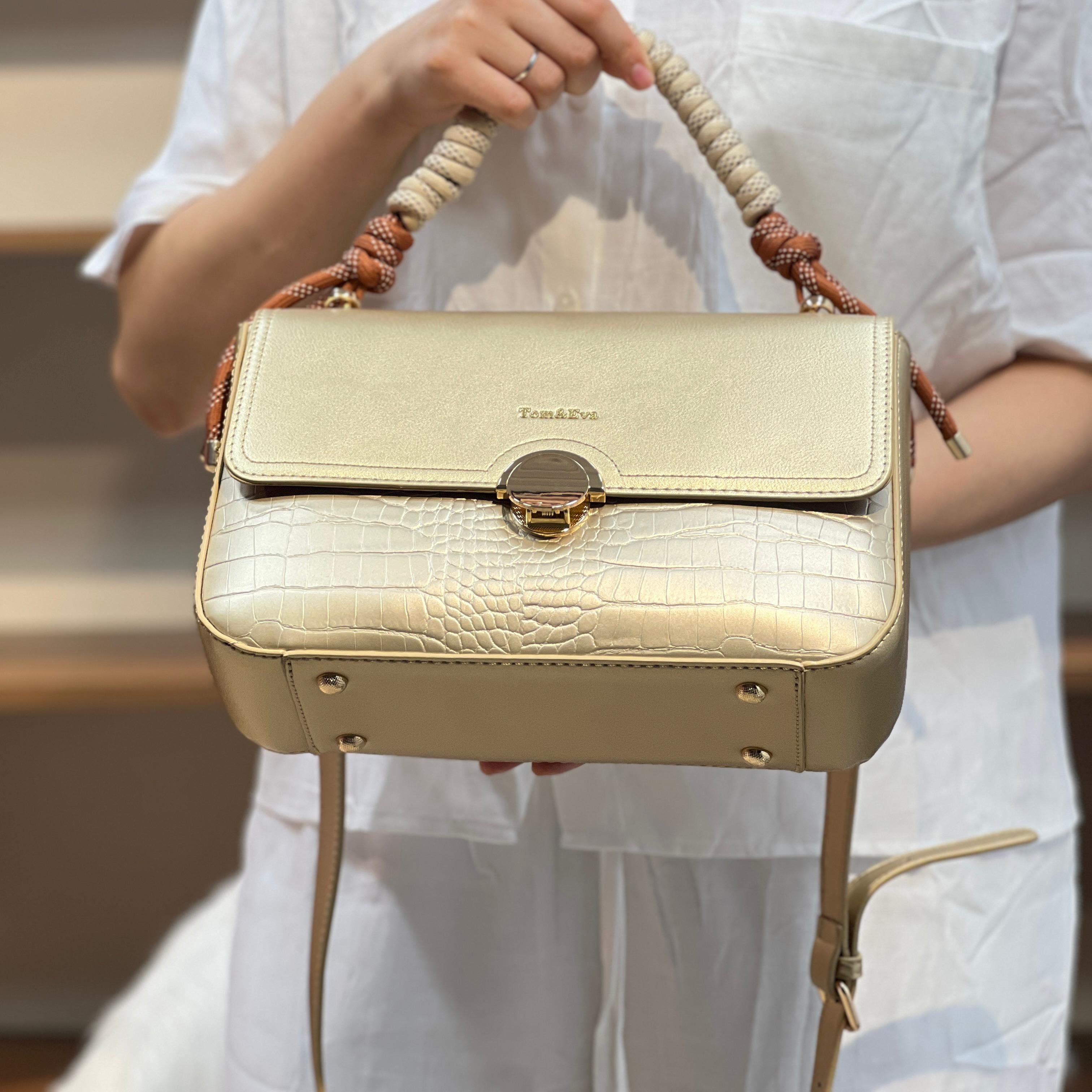 Sac à main avec anse en corde nouée et fermeture métallique.