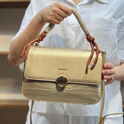 Sac à main avec anse en corde nouée et fermeture métallique.