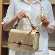 Sac à main avec anse en corde nouée et fermeture métallique.