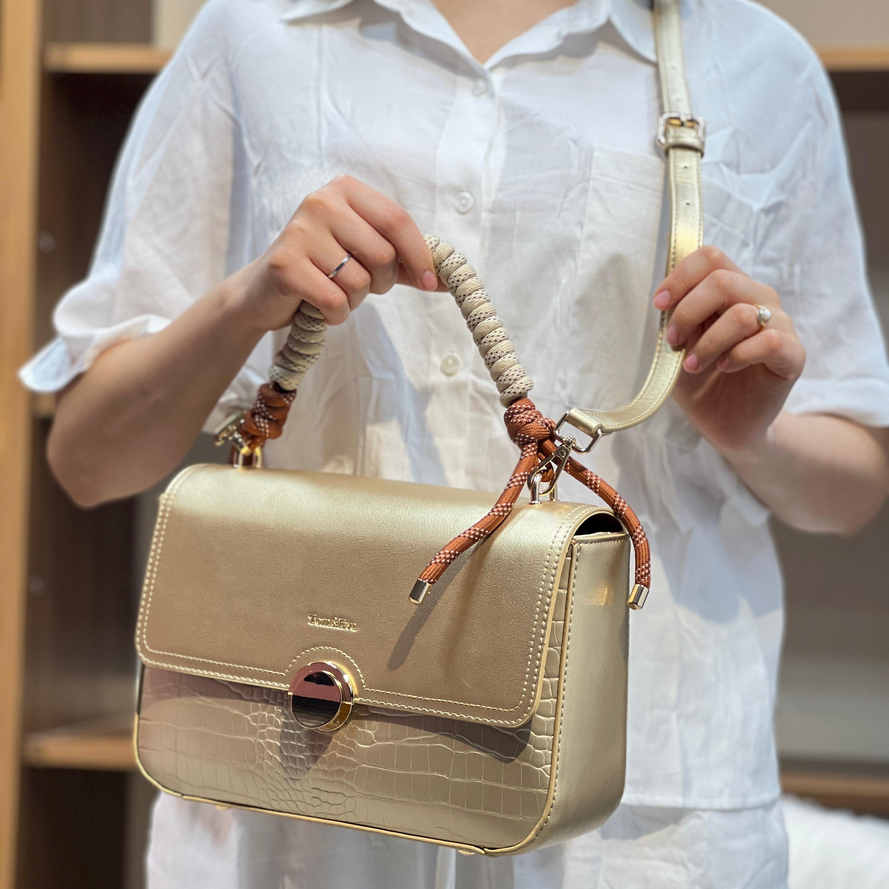 Sac à main avec anse en corde nouée et fermeture métallique.