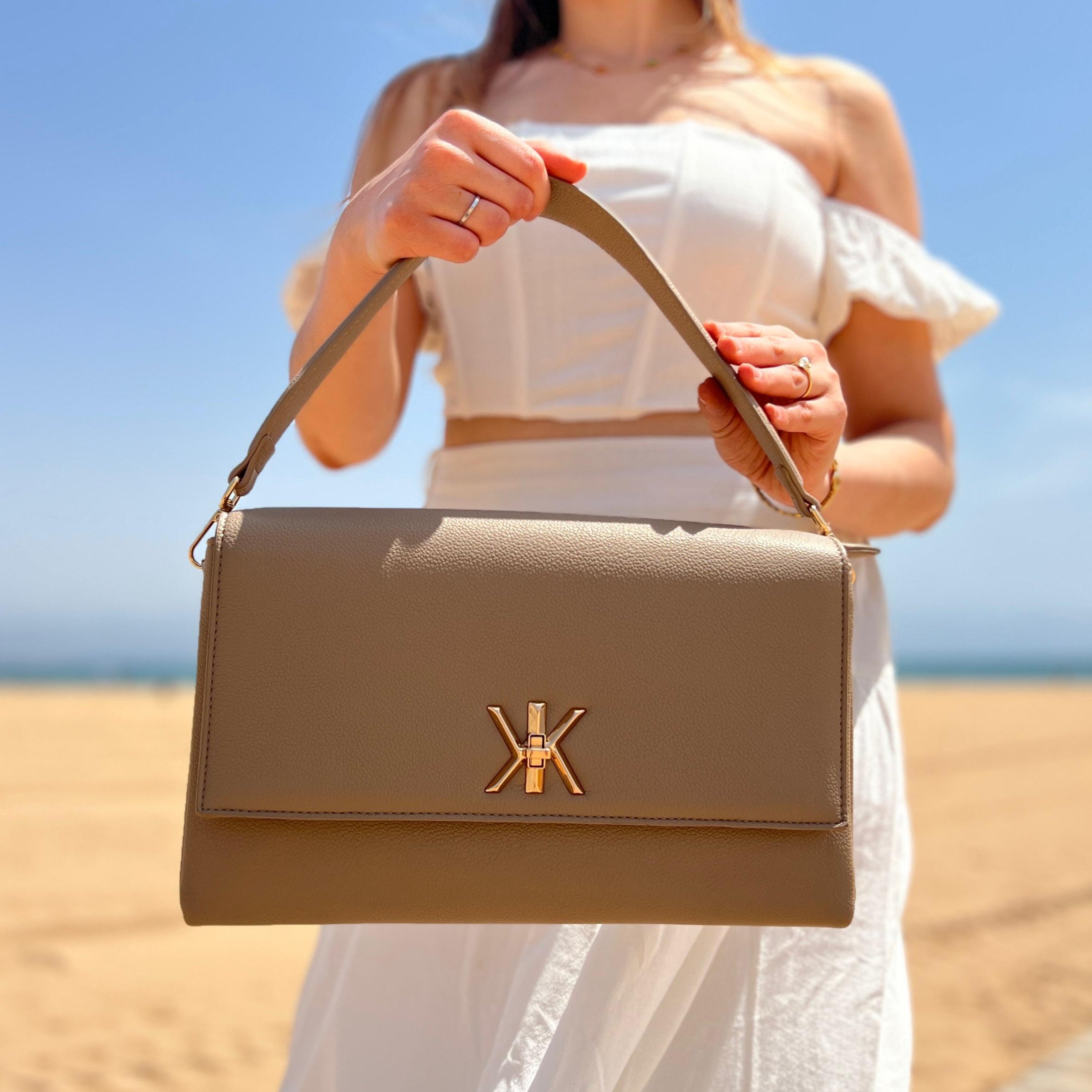 Pochette noire avec anse et bandoulière décorée de détails dorés