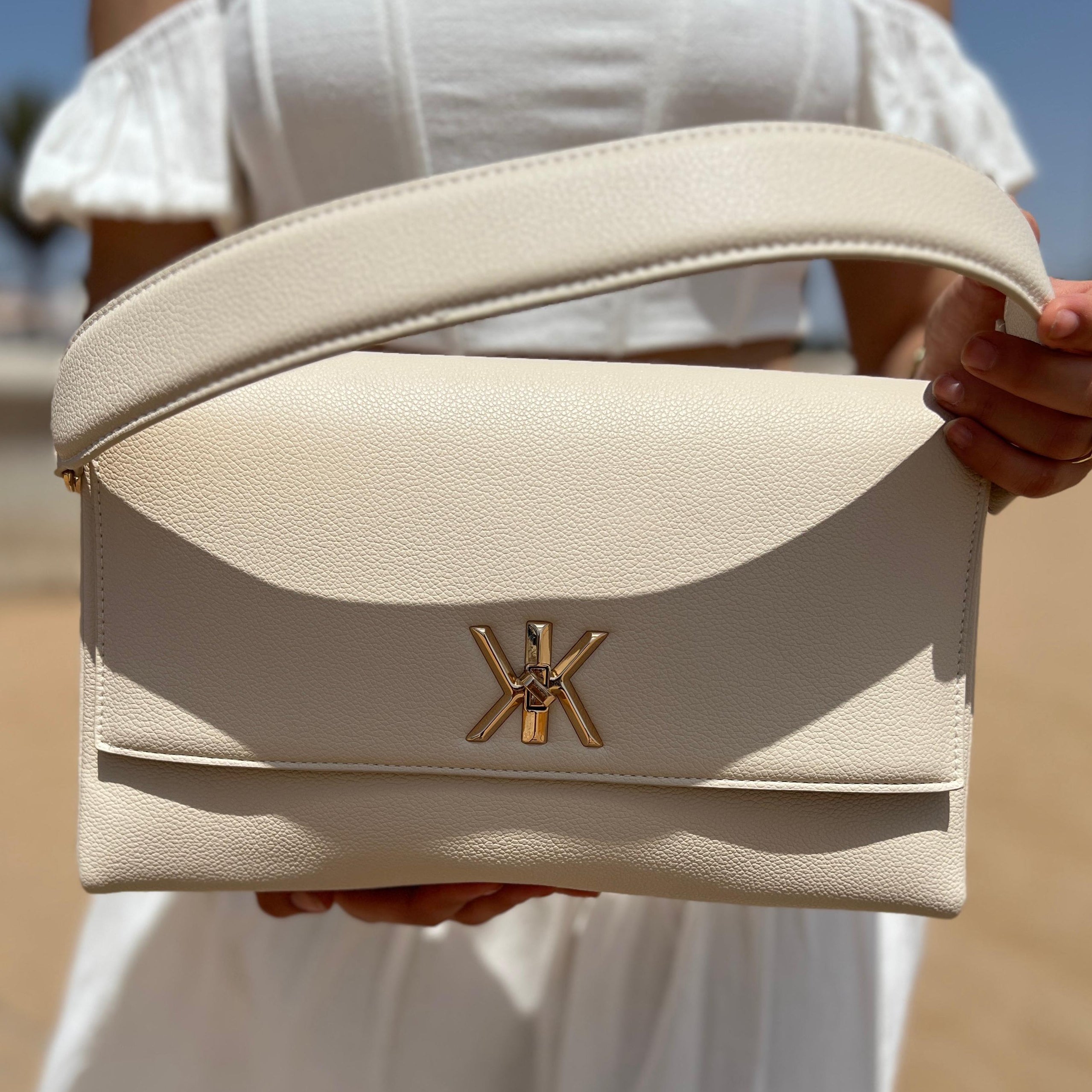 Pochette noire avec anse et bandoulière décorée de détails dorés