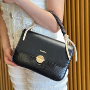 Sac à main avec anse en corde nouée et fermeture métallique.