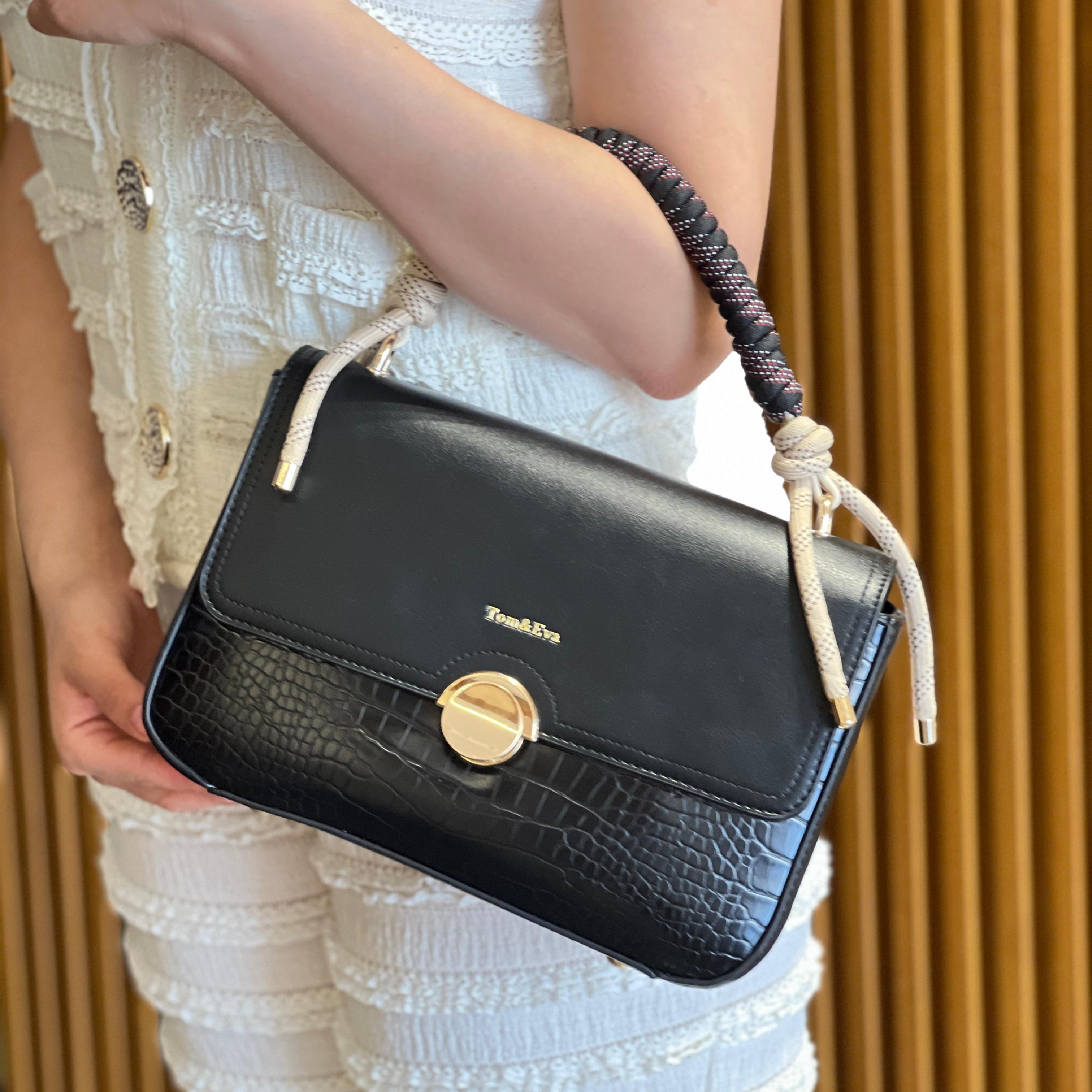 Sac à main avec anse en corde nouée et fermeture métallique.